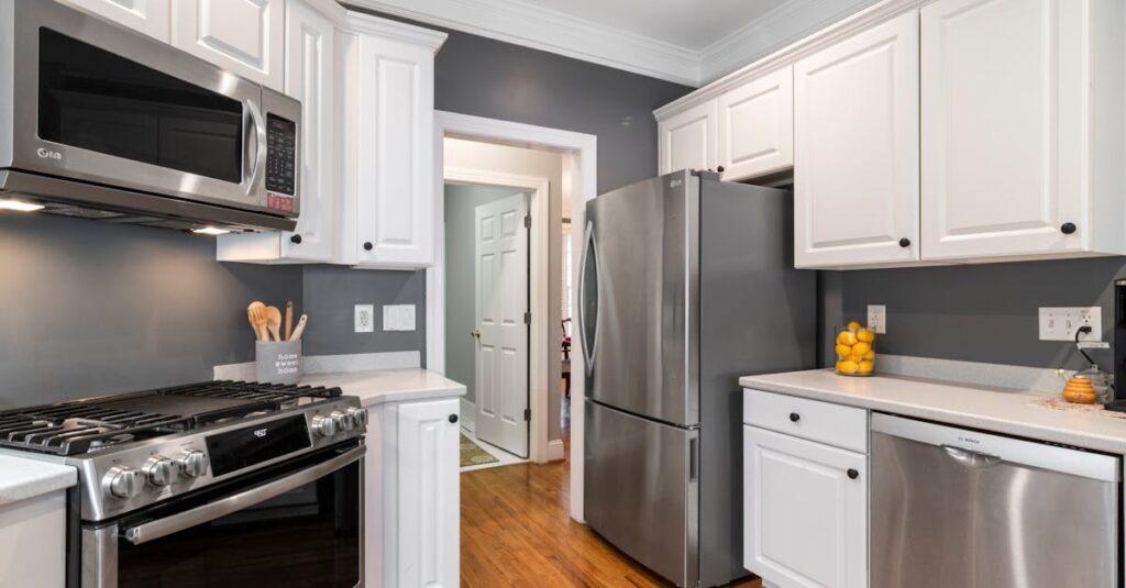 Silver Refrigerator Beside White Wooden Kitchen Cabinets