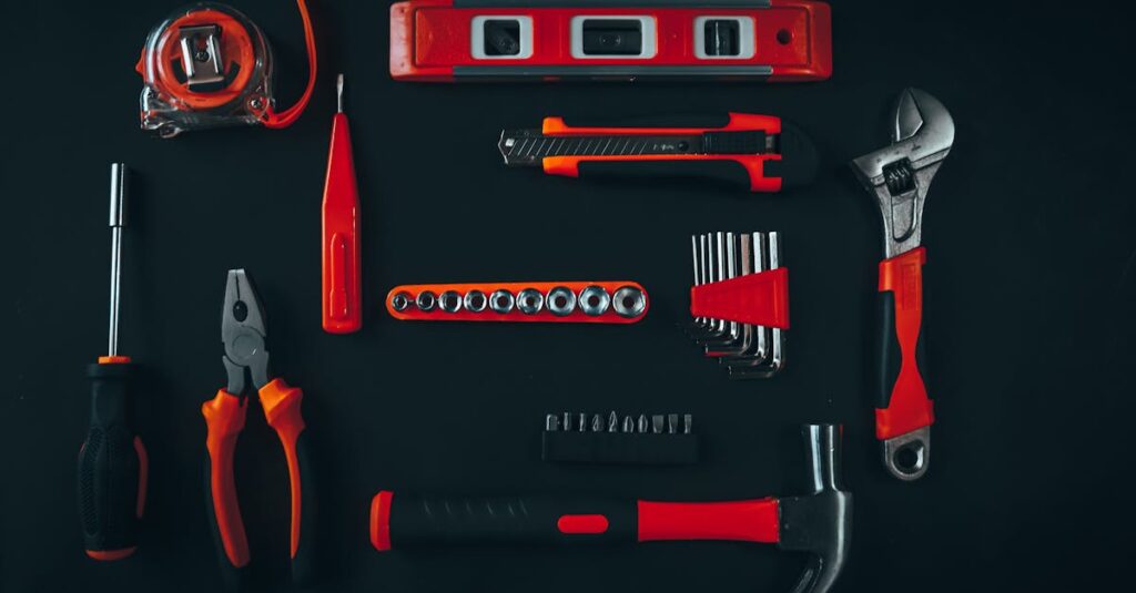 Top view arrangement of various repair tools including pliers hammer screwdriver and tape measure placed on black table